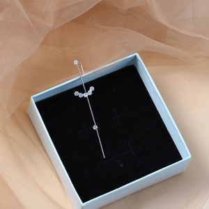 Detail of silver geometric ear wrap with zircon petals in a light blue jewelry box
