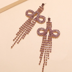 Detail of long tassel earrings featuring purple rhinestones and a gold-tone bow design