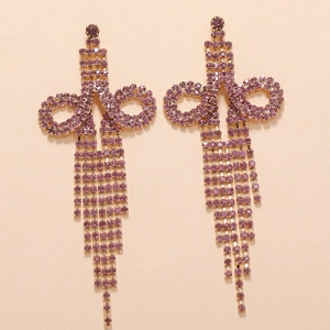 Close-up of elegant gold earrings featuring purple rhinestones and long tassel chains