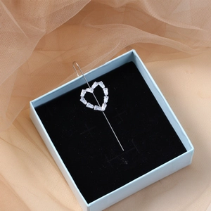 Detail view of heart-shaped silver earring with rectangular zircons in a gift box