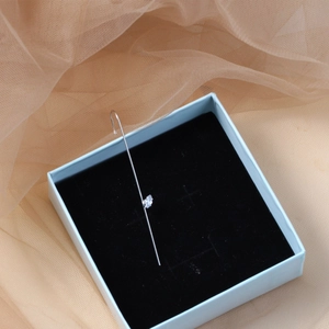 Minimalist silver ear cuff with marquise-cut zircon on a black velvet jewelry box