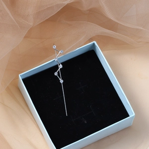 Detail of silver geometric ear cuff with sparkling zircons on blue jewelry box