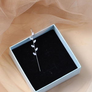 Macro detail of leaf ear climber with marquise stones in a light blue jewelry gift box