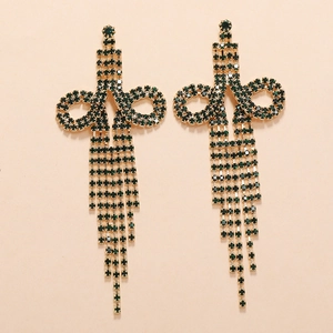 Detail of long emerald green rhinestone tassel earrings with golden bow knot structure