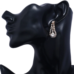 Close-up of teardrop tassel earrings with golden metal base and sparkling rhinestones