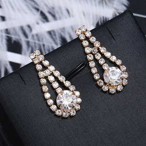 Macro detail of long gold tassel earrings with clear sparkling rhinestones on black velvet