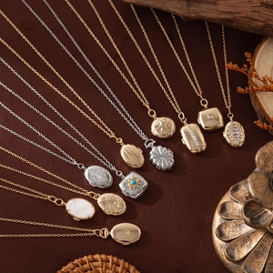 Flat lay of vintage gold and silver locket necklaces with engraved floral patterns