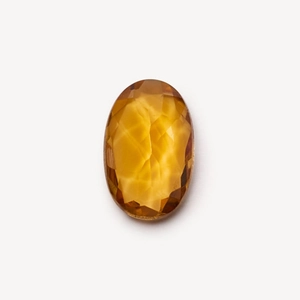 Macro shot of an oval citrine gemstone with orange hues and faceted cut on white background