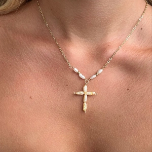 Gedetailleerd aanzicht van een gouden ketting met een kruisvormige parelhanger