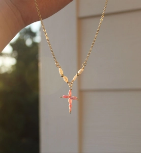 Gedetailleerde foto van gouden ketting met parelkruis hanger vastgehouden met de hand