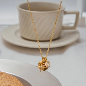 Dettaglio della collana dorata con ciondoli a cuore, stella e pietra preziosa