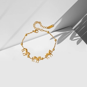 Elegante pulsera de acero inoxidable dorado con tres dijes de cebra sobre fondo blanco