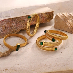 Gold Tubogas stretch bracelets with green zircon stones set on a natural stone background