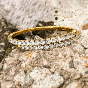 Makro-Detail des luxuriösen zweireihigen Zirkonia-Armbands in Gold auf Naturstein