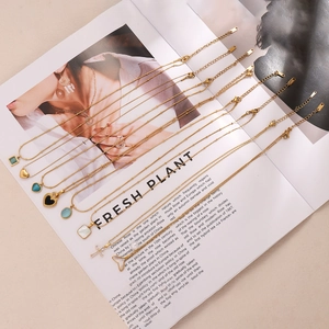 Gold plated shell pendant necklace collection with assorted charms on a magazine background