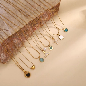 Elegant gold titanium steel necklace collection featuring diverse gemstone pendants on a rock