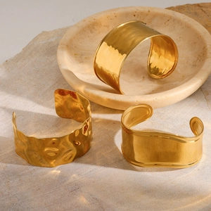 Détail de bracelets manchettes en acier inoxydable plaqué or 18 carats martelé et poli