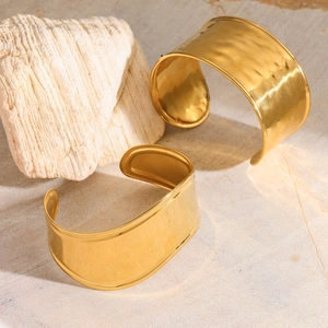 Détails de la texture martelée sur deux bracelets manchettes ouverts dorés minimalistes