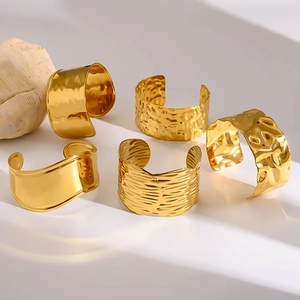 Détail de cinq bracelets dorés ondulés aux surfaces texturées sur un présentoir épuré