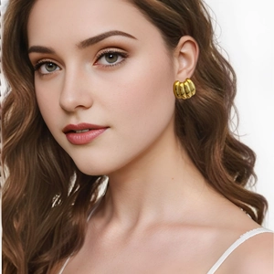 Boucles d'oreilles dorées polies au design croissant nervuré portées par un mannequin