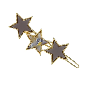 Detail view of a gold hair clip featuring three star shapes in marble and purple enamel finish