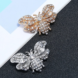 Detailed macro view of gold and silver bee brooches with sparkling crystal rhinestones