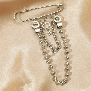 Silver punk key brooch with chains and handcuffs on elegant champagne silk fabric