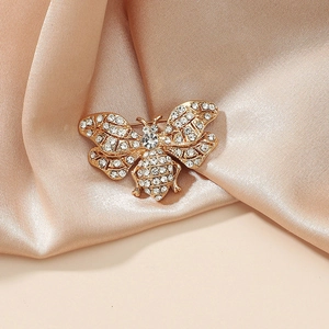 Elegant gold bee brooch with sparkling crystals on champagne silk background