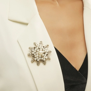 Détail d'une broche flocon de neige dorée vintage avec perles sur un revers