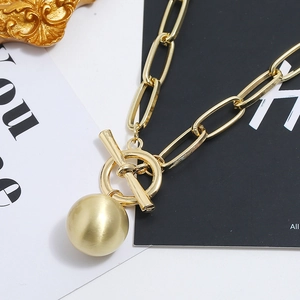 Primo piano della collana a catena dorata con chiusura a T e pendente a sfera opaca