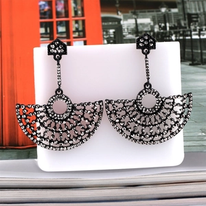 Macro detail of retro fan-shaped hollow earrings with grey rhinestones on a card