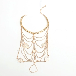 Détail de la chaîne de cheville dorée multicouche avec pendentifs pièces et fermoir homard