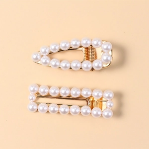2-piece set of elegant pearl hair clips with golden alloy base on a soft beige background