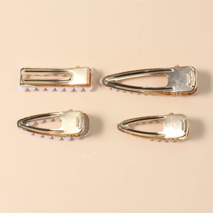 Elegant four-piece gold alloy hair clip set with white faux pearls on an apricot background