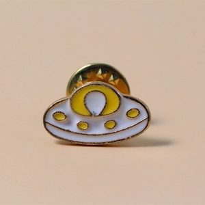 Creative UFO enamel pin with yellow and white finish on a polished gold-plated metal base