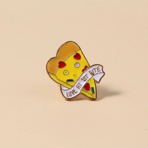 Macro shot of cute pizza enamel pin with heart pepperoni and Love At 1st Bite text