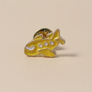 Detailed view of a cute yellow cartoon airplane enamel pin with gold metal framing