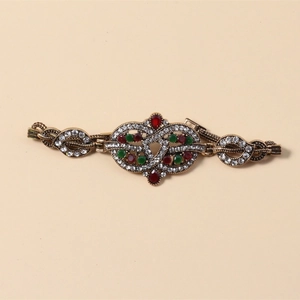 Detailaufnahme des Vintage-Goldarmbands mit hohlen Mustern und roten sowie grünen Steinen
