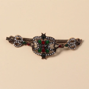 Detaillierte Makroaufnahme von Vintage-Armband mit roten und grünen Steinen in Altgold