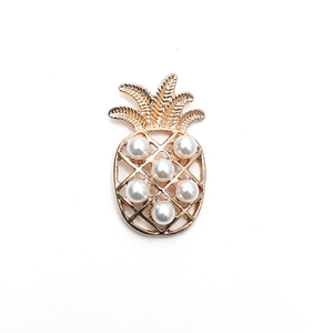 Détail d'une broche en forme d'ananas doré ornée de perles et de feuilles ciselées
