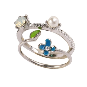 Detail of silver floral ring with blue enamel petals, white pearl and green leaf