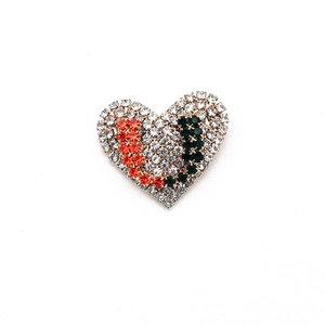Spilla a cuore alla moda con strass bianchi, arancioni e verde scuro su fondo bianco