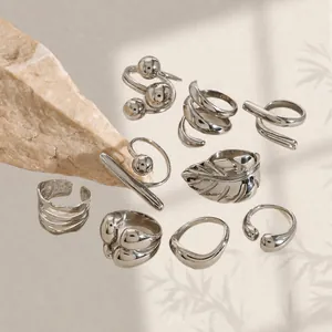 Polished silver geometric stainless steel rings set displayed on a beige background