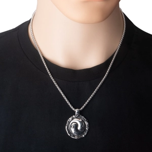 Close-up of a vintage stainless steel Yin Yang pendant with intricate relief details