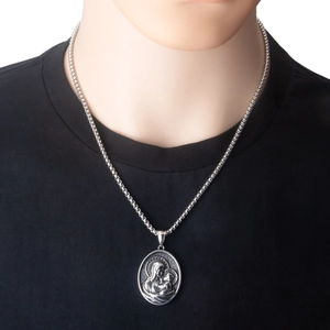 Detailopname van een zilveren ketting met ovale religieuze reliëf hanger op een model