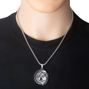 Close-up van een zilveren roestvrijstalen wolfskop hanger aan een kralenketting voor heren