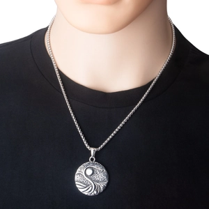 Close-up van de roestvrijstalen levensboom hanger ketting op een zwart t-shirt