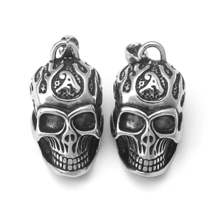 Détail de pendentifs crâne vintage avec gravure lettre A et finition punk rétro