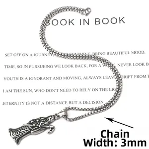 Détail du pendentif faucheuse punk vintage avec chaîne box 3mm sur un livre blanc
