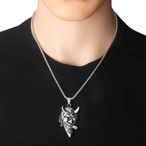 Gros plan d'un pendentif masque de démon punk argenté pour homme de style vintage